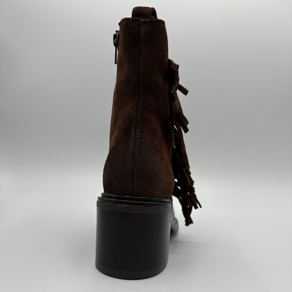 A dark brown suede ankle boot with fringe detailing on the side and a chunky black block heel, shown from a rear three-quarter view against a neutral gray background.