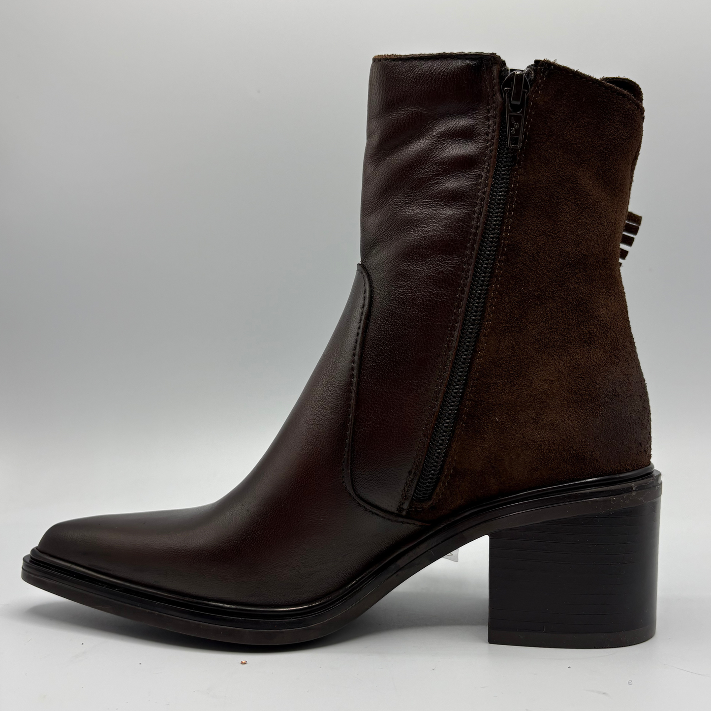 A dark brown ankle boot with a mix of smooth leather and suede textures, featuring a side zipper, pointed toe, and block heel, shown against a neutral gray background.