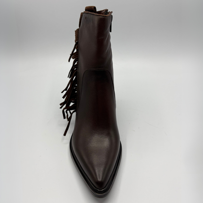 A dark brown leather ankle boot with a pointed toe and fringe detailing along the side, photographed against a neutral light gray background.