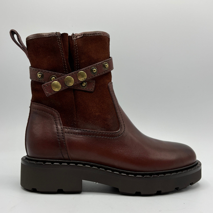 Brick red motorcycle boot with gold accents on the accent strap around ankle on a white background