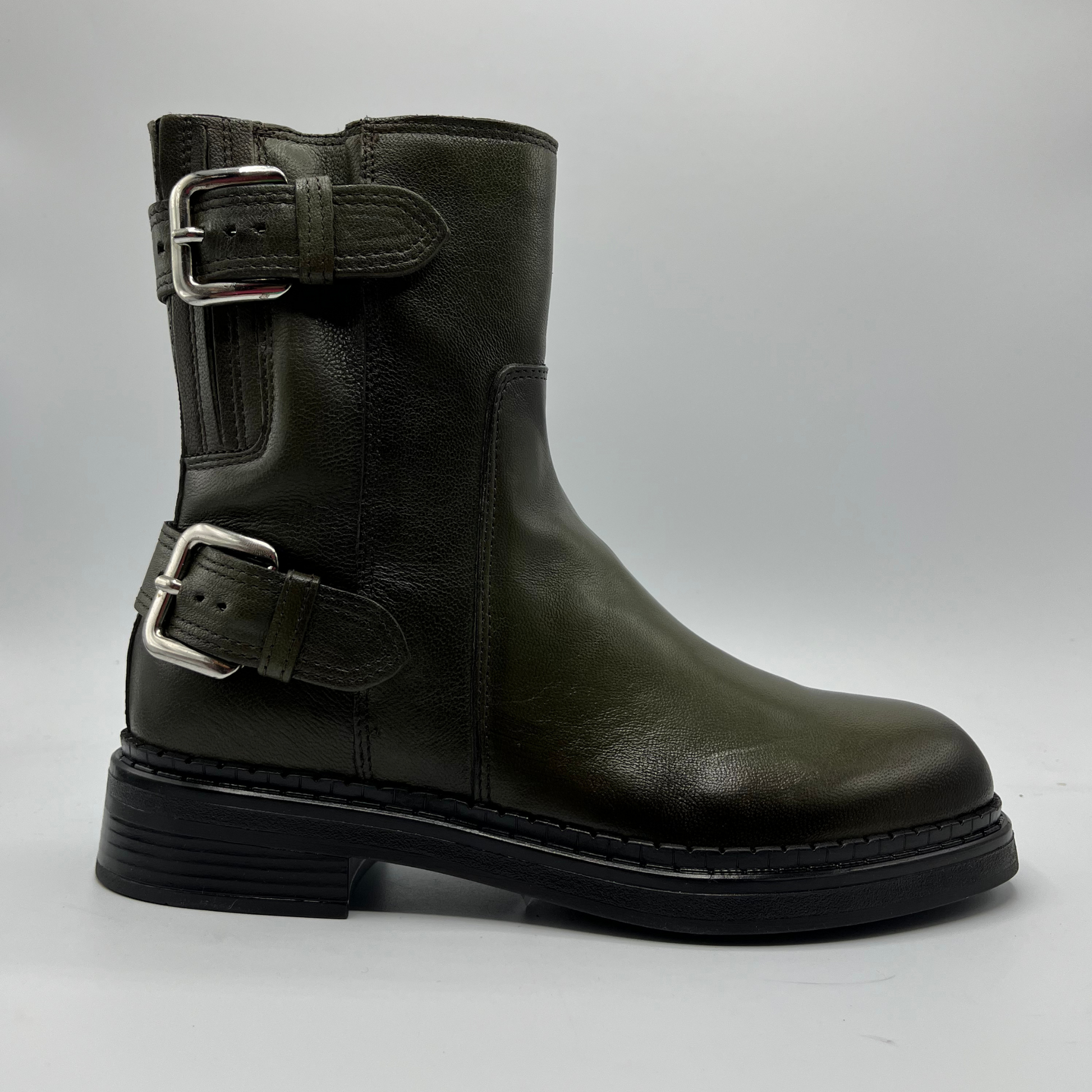 Green leather boot with buckles on a gray background