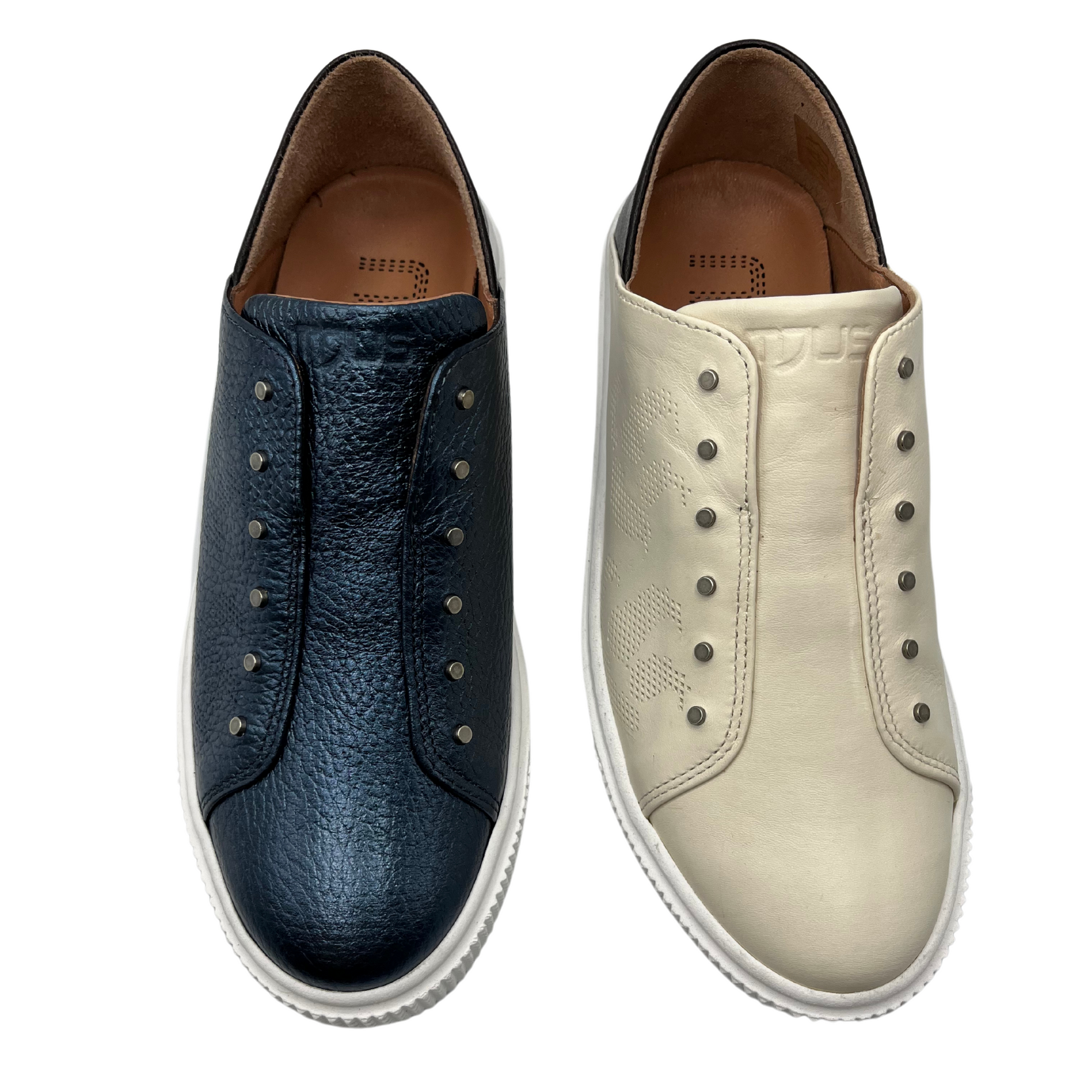 Top view of two leather sneakers side by side. One is navy and one is latte. Both have white rubber outsoles