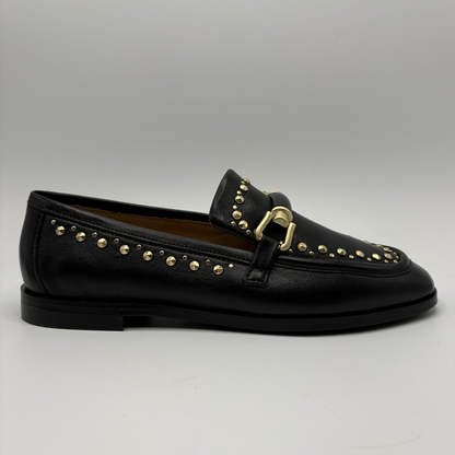 Black loafer with gold studs and buckle on a gray background