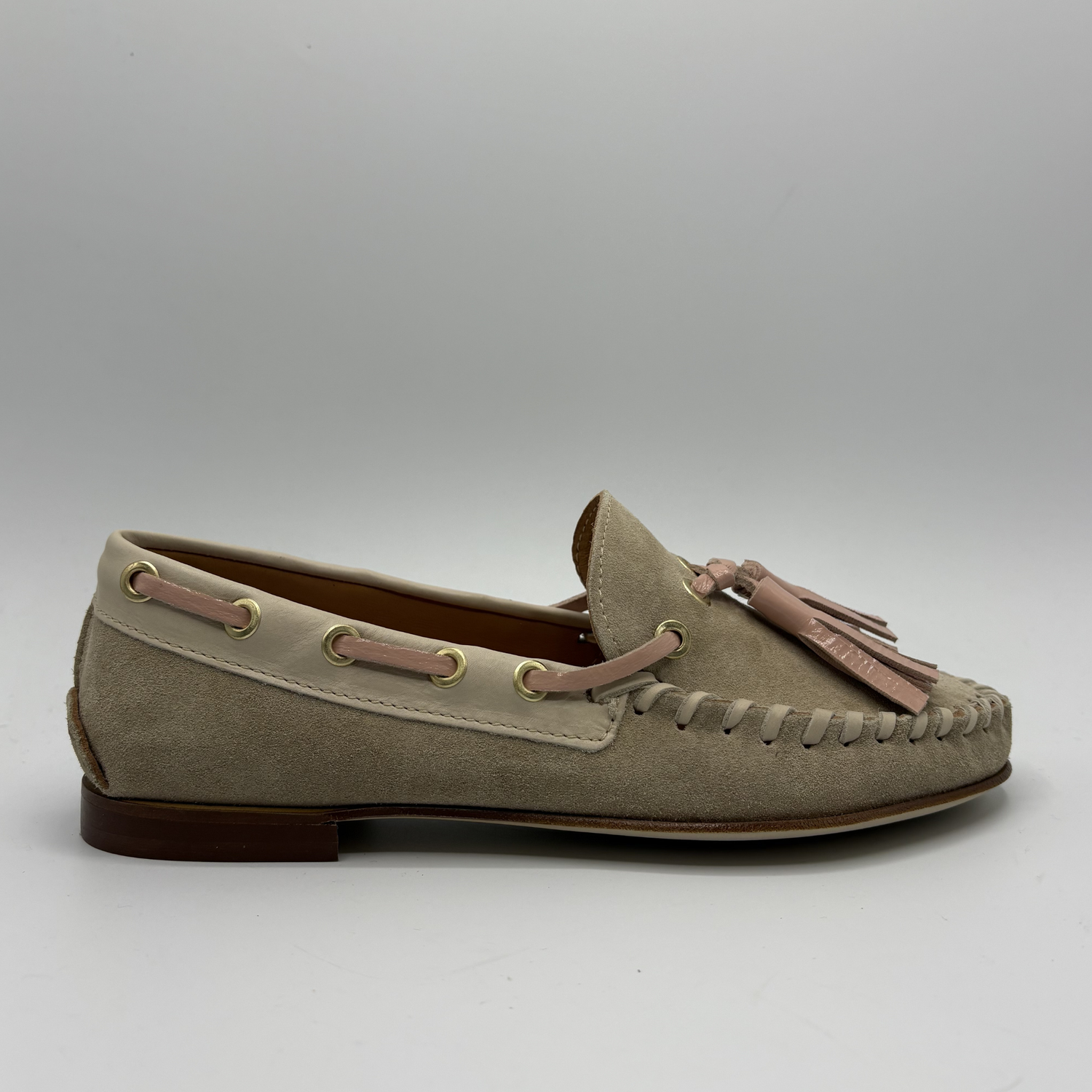 Beige loafer with tassels on a gray background