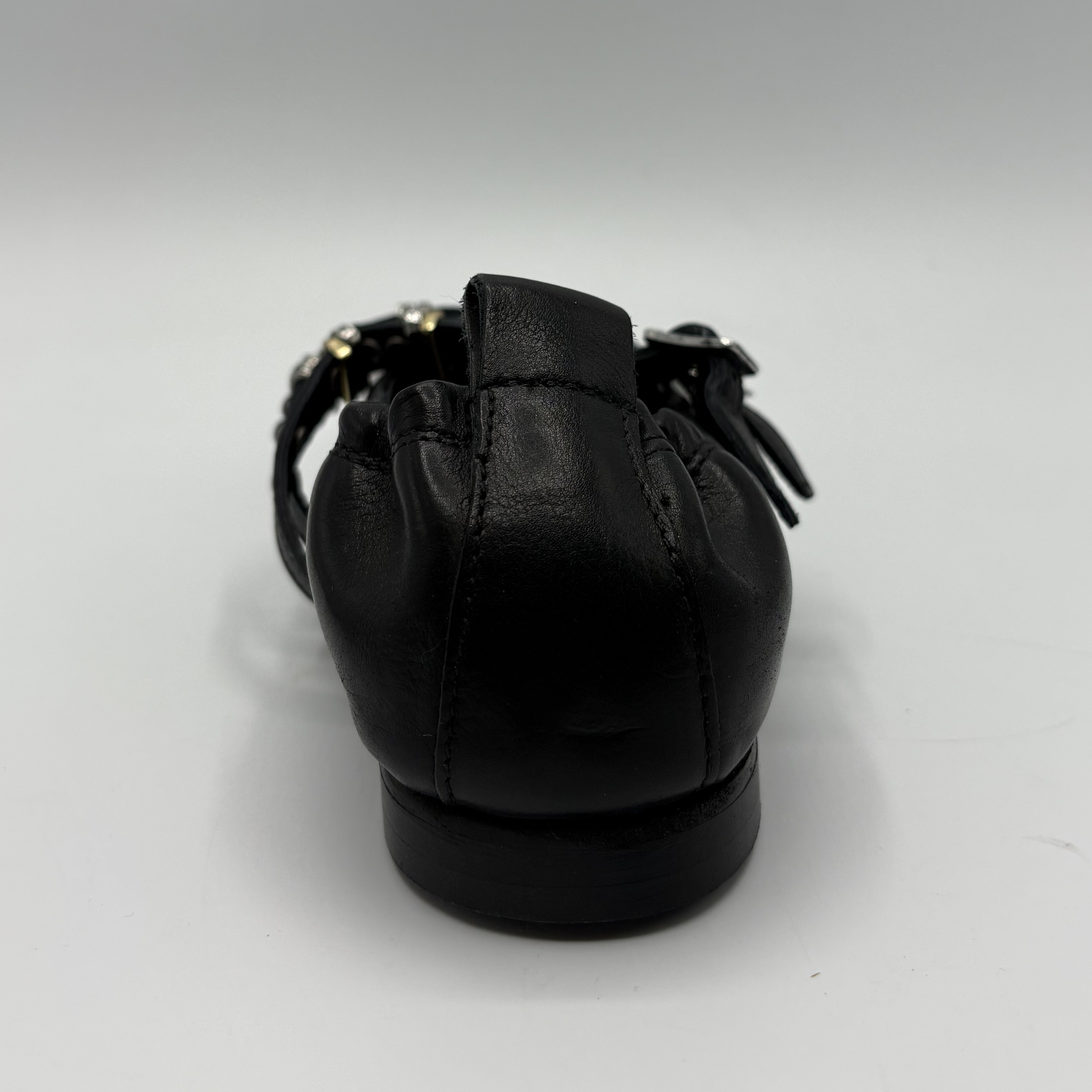 Black flat shoe with a strap on a white background