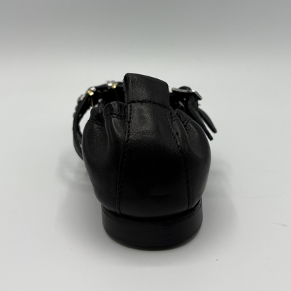 Black flat shoe with a strap on a white background