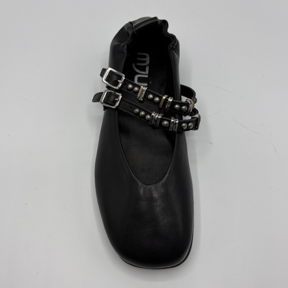 Black flat shoe with buckles on a gray background