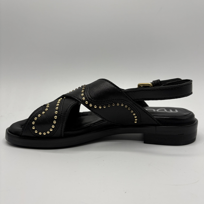 Black sandal with gold studs on a gray background