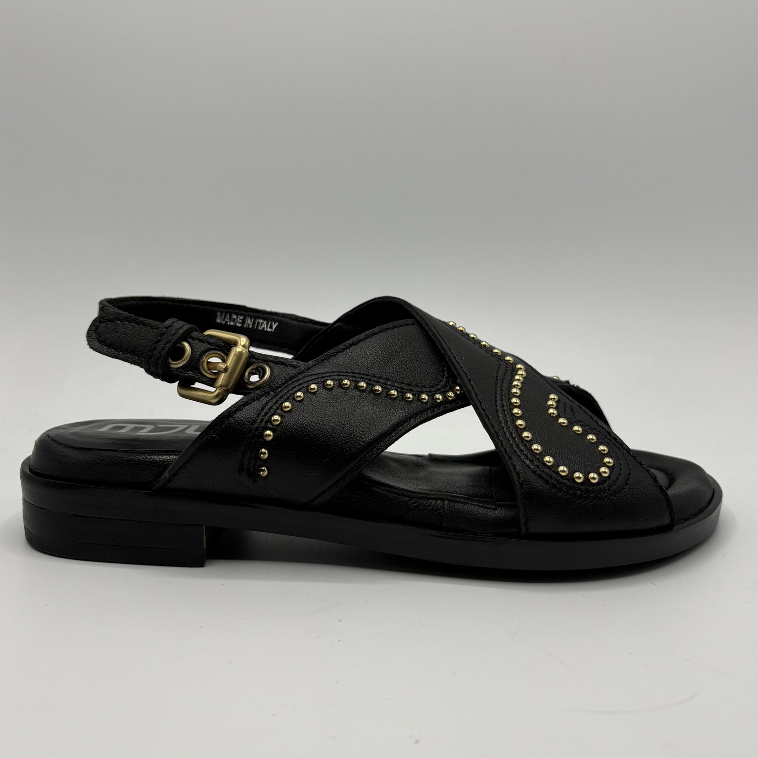 Black sandal with gold details on a gray background