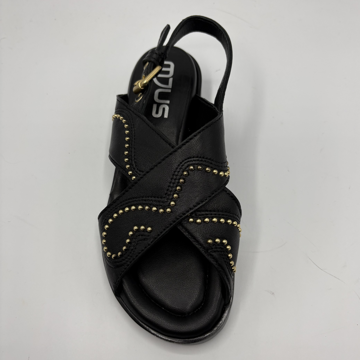 Black sandal with gold accents on a light gray background