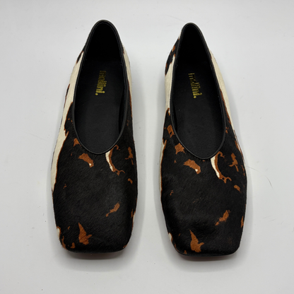 Pair of cow print patterned shoes on a white background