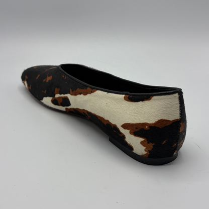 Black and white cow print flat shoe on a gray background