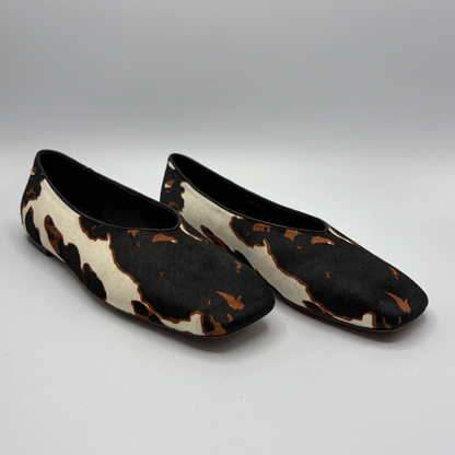 Pair of cow print patterned shoes on a gray background