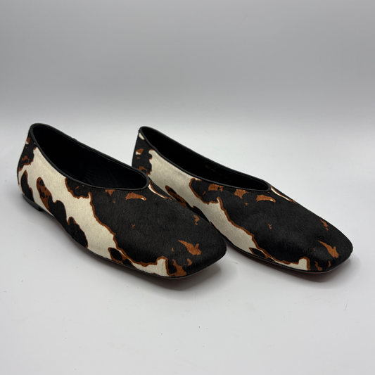 Pair of cow print patterned shoes on a gray background