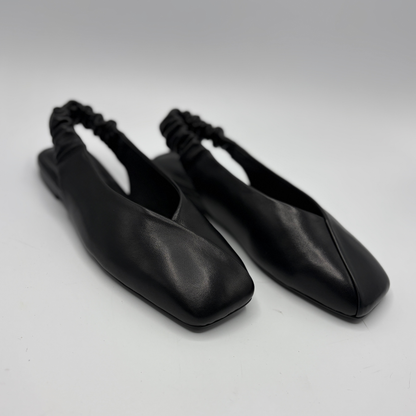 Pair of black leather shoes with square toes on a light gray background