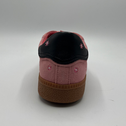 Back view of a pink suede sneaker with a black collar and a tan rubber outsole.