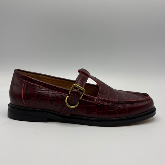 A single burgundy crocodile-embossed Mary Jane loafer with a gold buckle strap, shown in profile against a neutral gray background.
