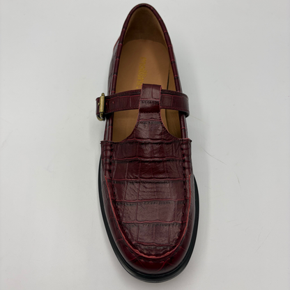A single burgundy crocodile-embossed leather Mary Jane loafer with a buckle strap, photographed from a top-down angle on a light gray background.