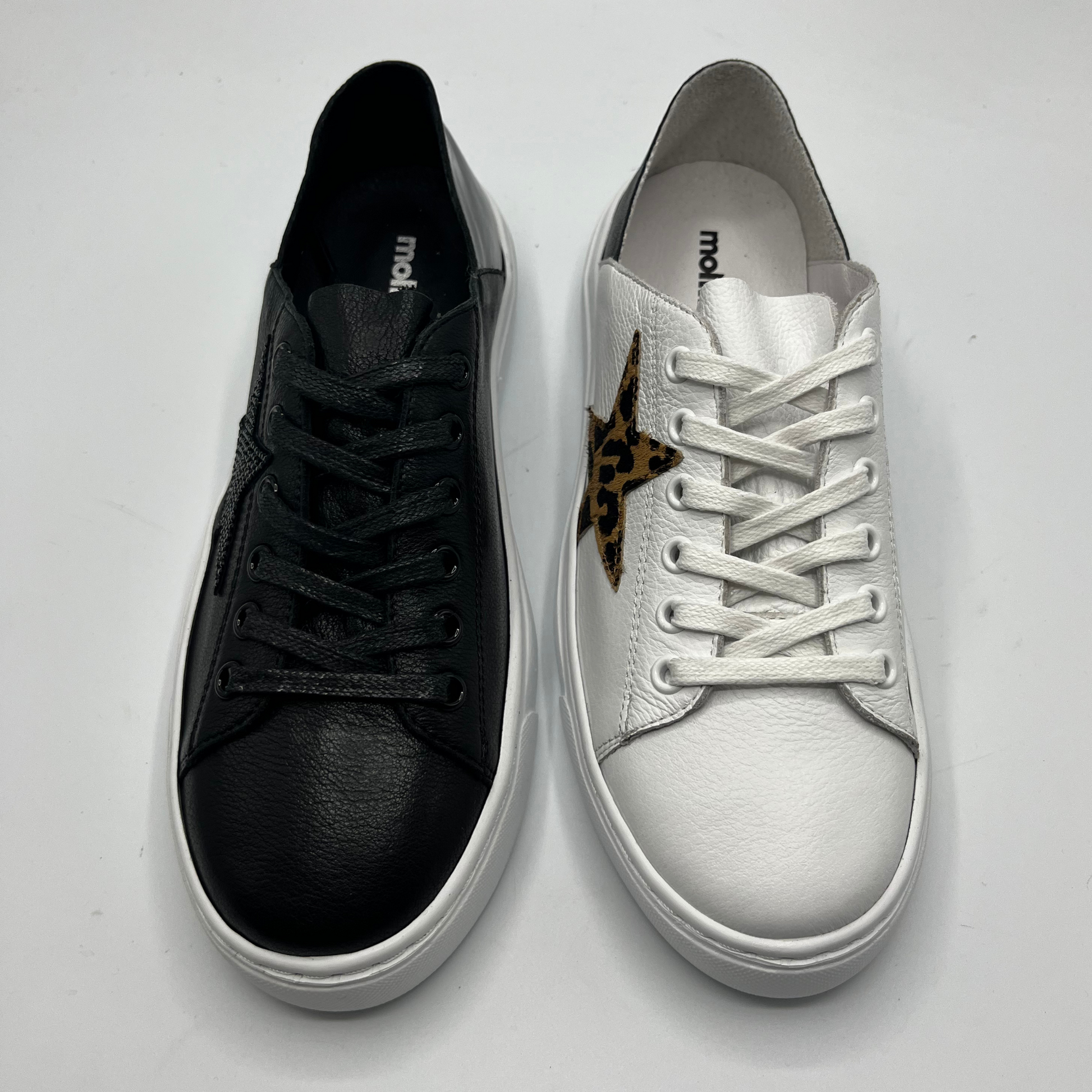 Top view of a black sneaker and a white leather sneaker