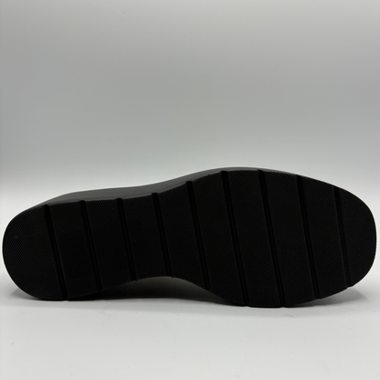 The black textured rubber outsole of a shoe, shown from a top-down view against a light gray studio background.