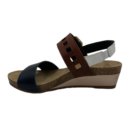 Left view of leather sandal with a large buckle strap with low wedge heel