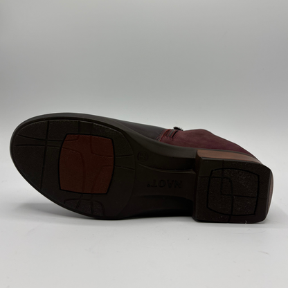 A dark burgundy leather ankle boot with side zipper details, photographed from a top-down angle on a light gray background.