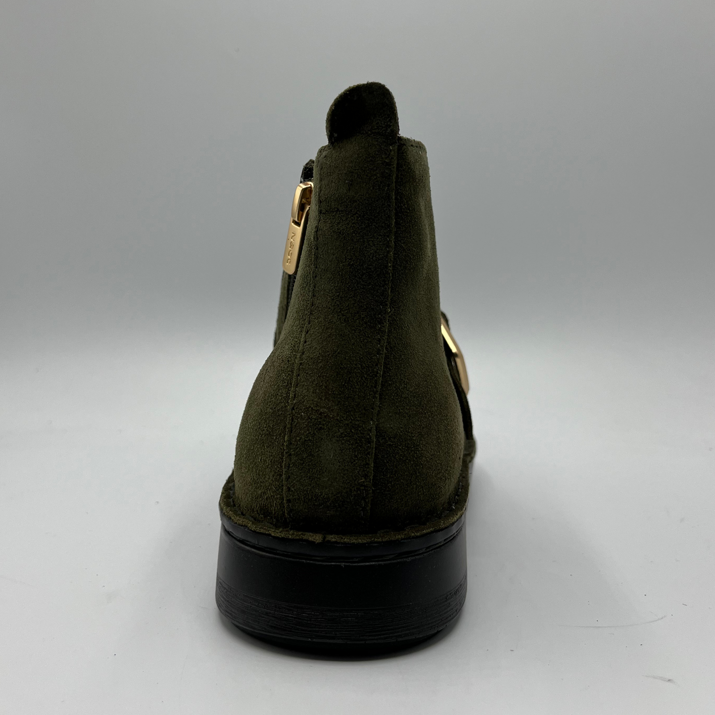 Green suede ankle boot with gold zipper on a gray background