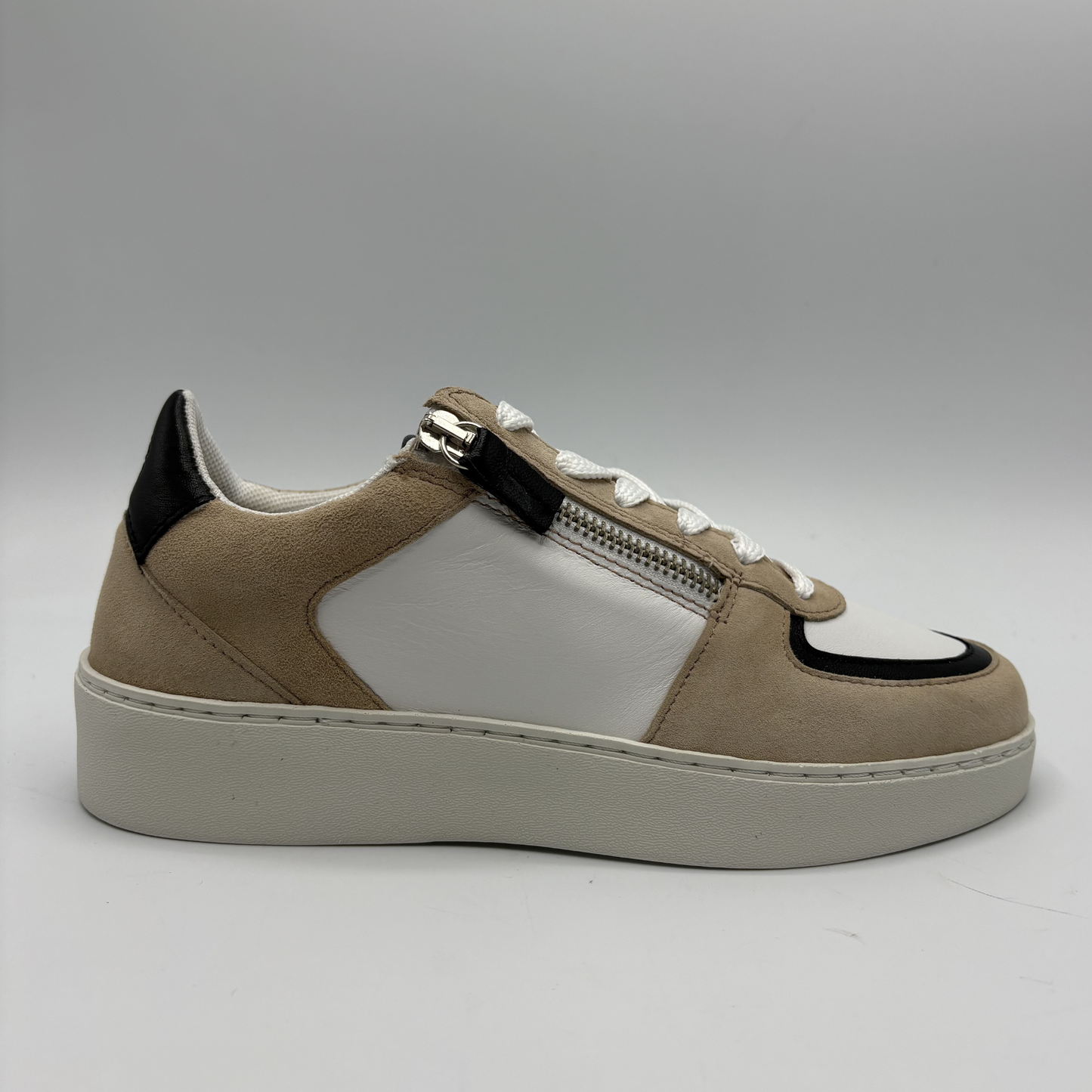 Right facing view of an almond, black and white sneaker with laces and a side zipper