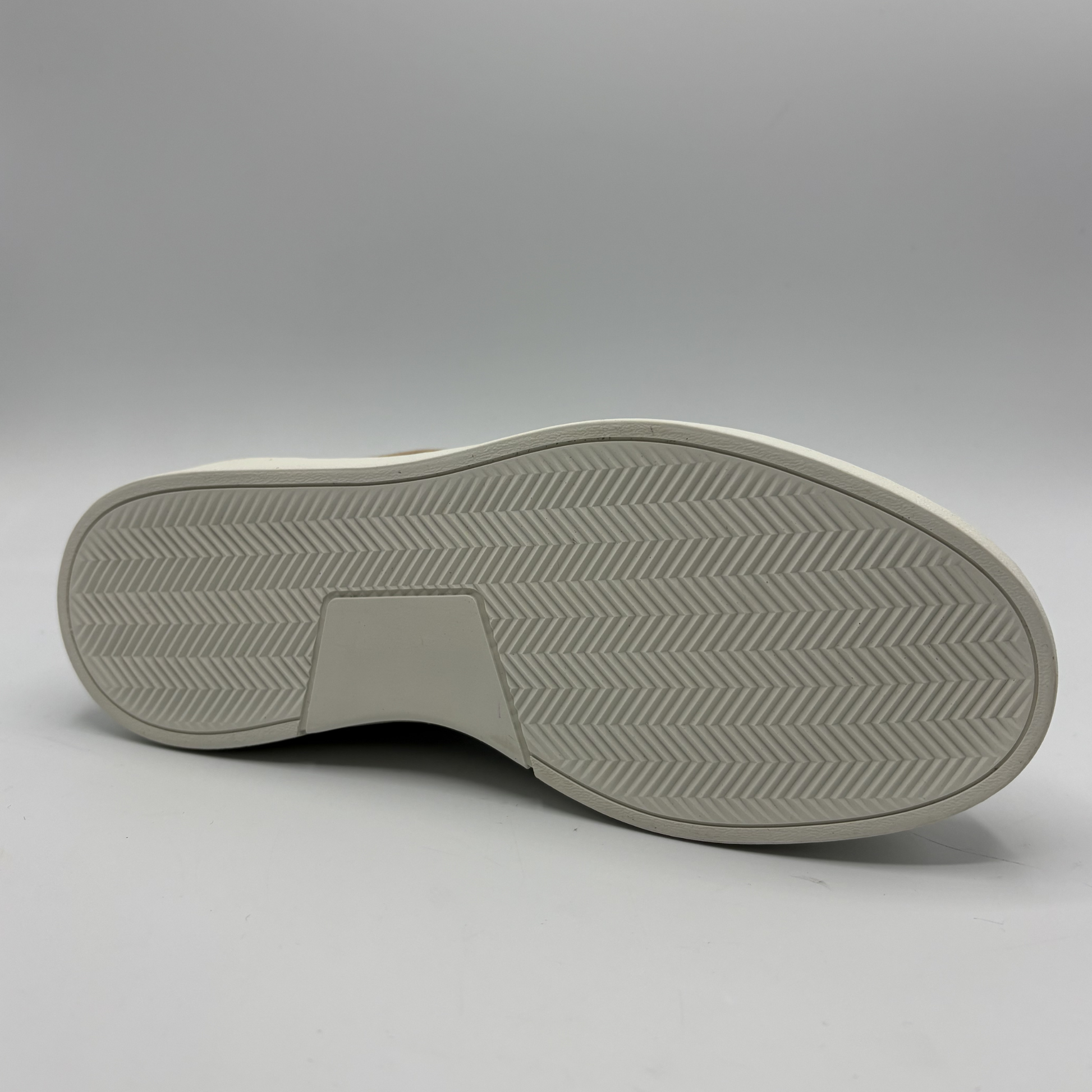 Bottom view of an almond, black and white sneaker with laces and a side zipper