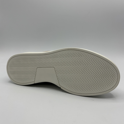 Bottom view of an almond, black and white sneaker with laces and a side zipper