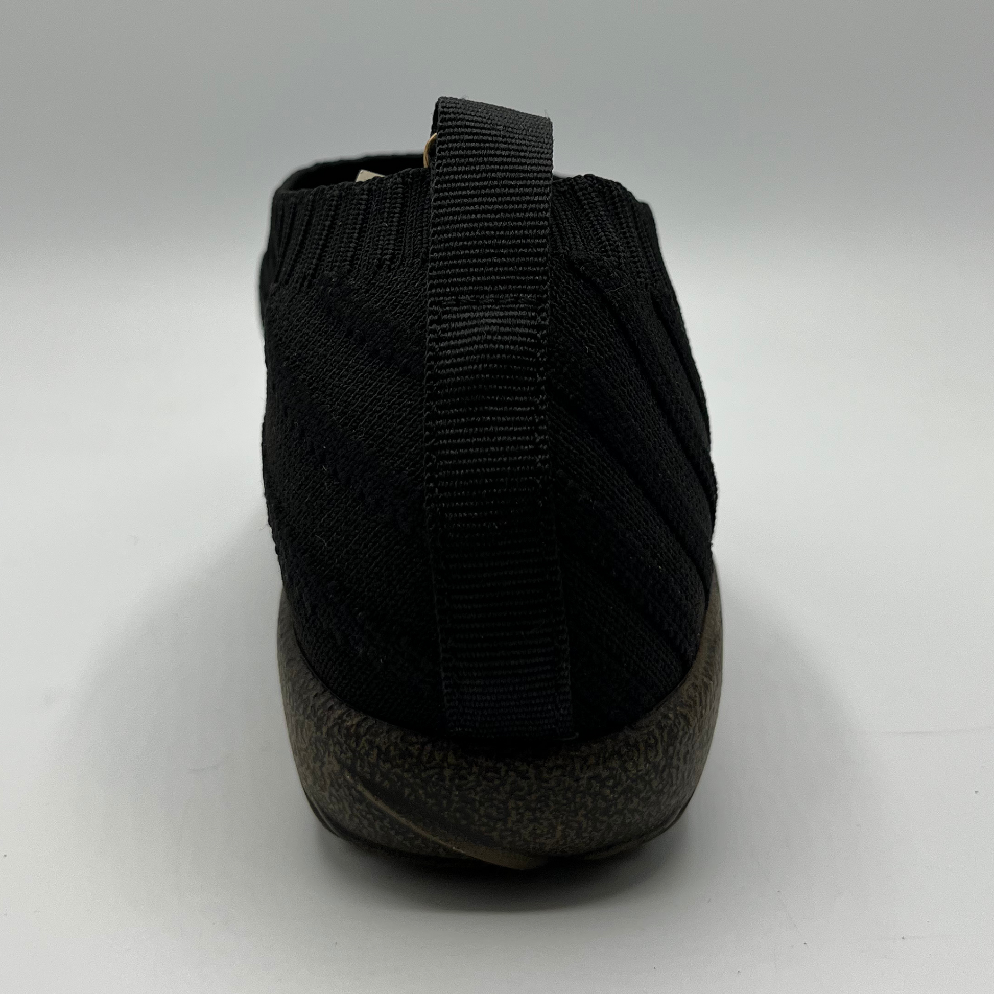 Black shoe with a textured sole on a white background