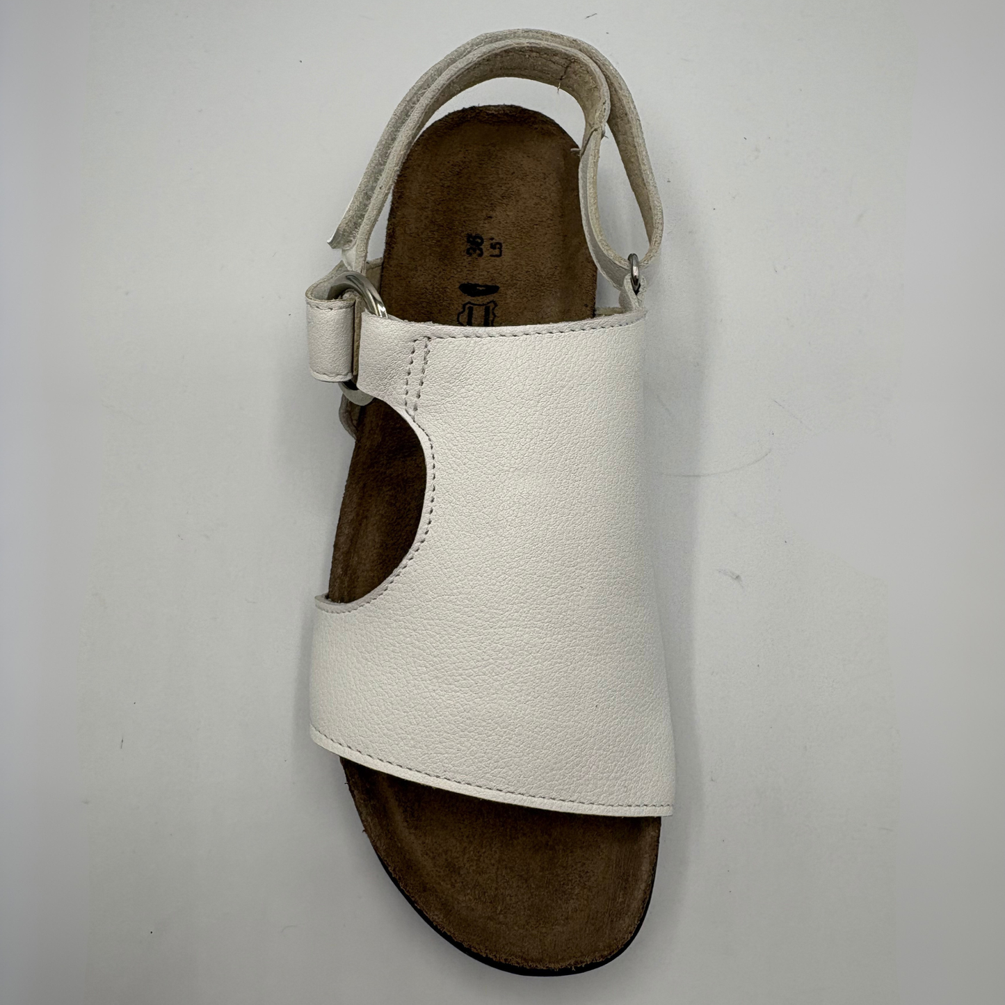 White sandal with brown sole on a light gray background