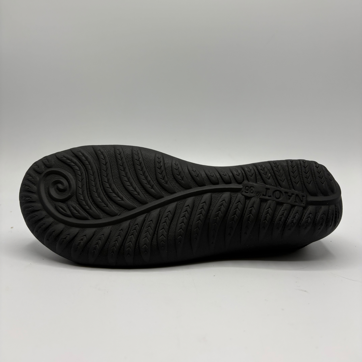 The black rubber outsole of a shoe, showing textured tread patterns