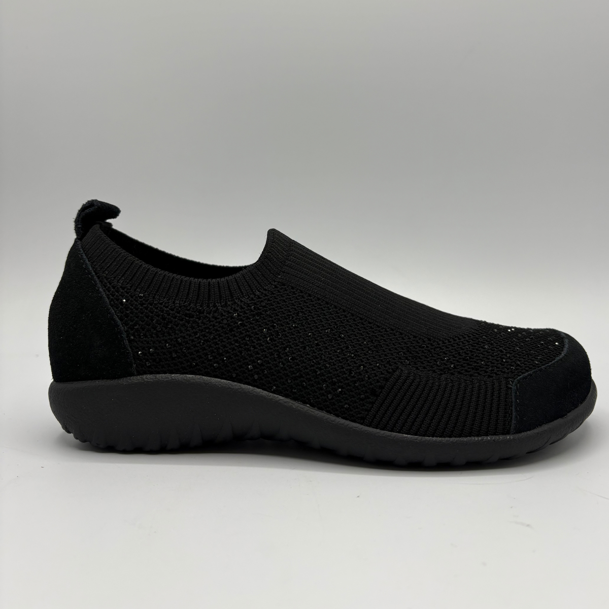A single black knit sneaker shown in a side profile on a light gray background.