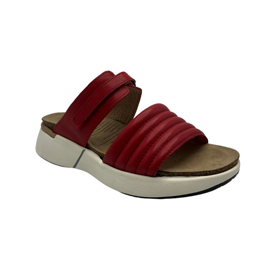 45 degree angled view of red leather slip on sandal with white rubber outsole, padded front strap and open toe
