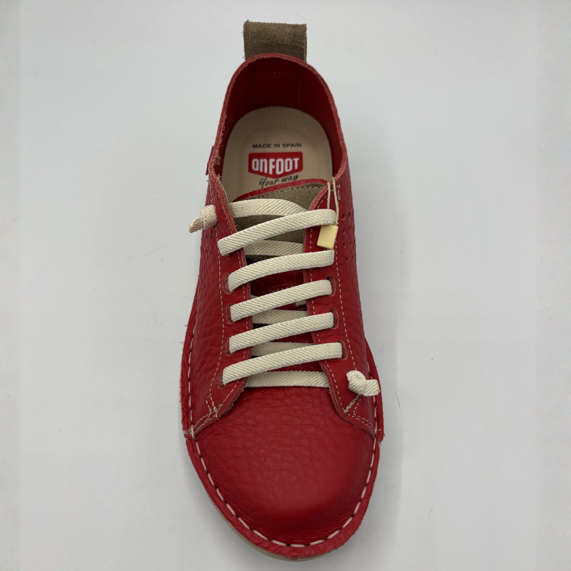 Red shoe with white laces on a light gray background