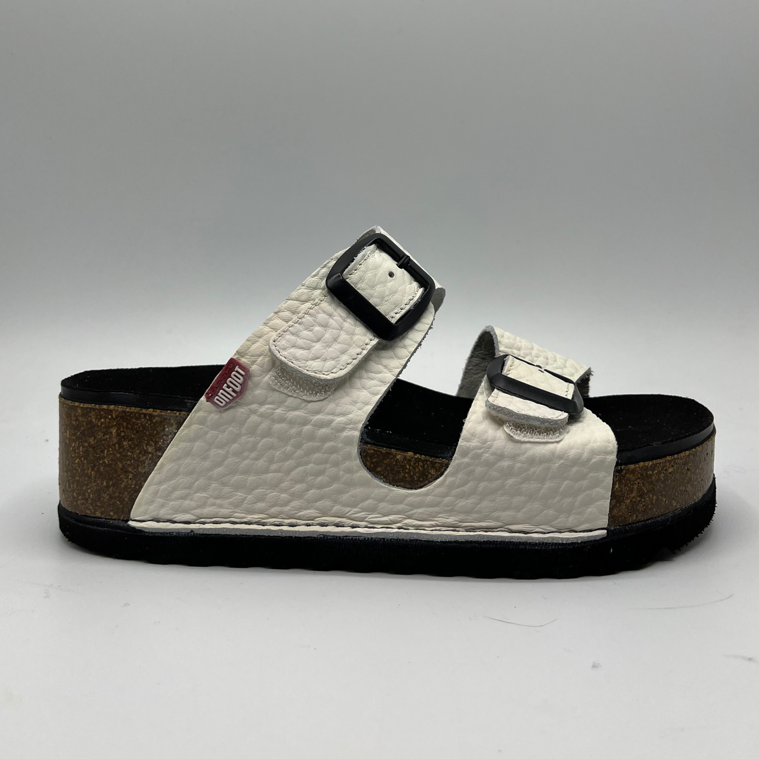 Right facing view of a platform sandal in a pebbled white leather.  Two thick straps across with adjustable buckles.