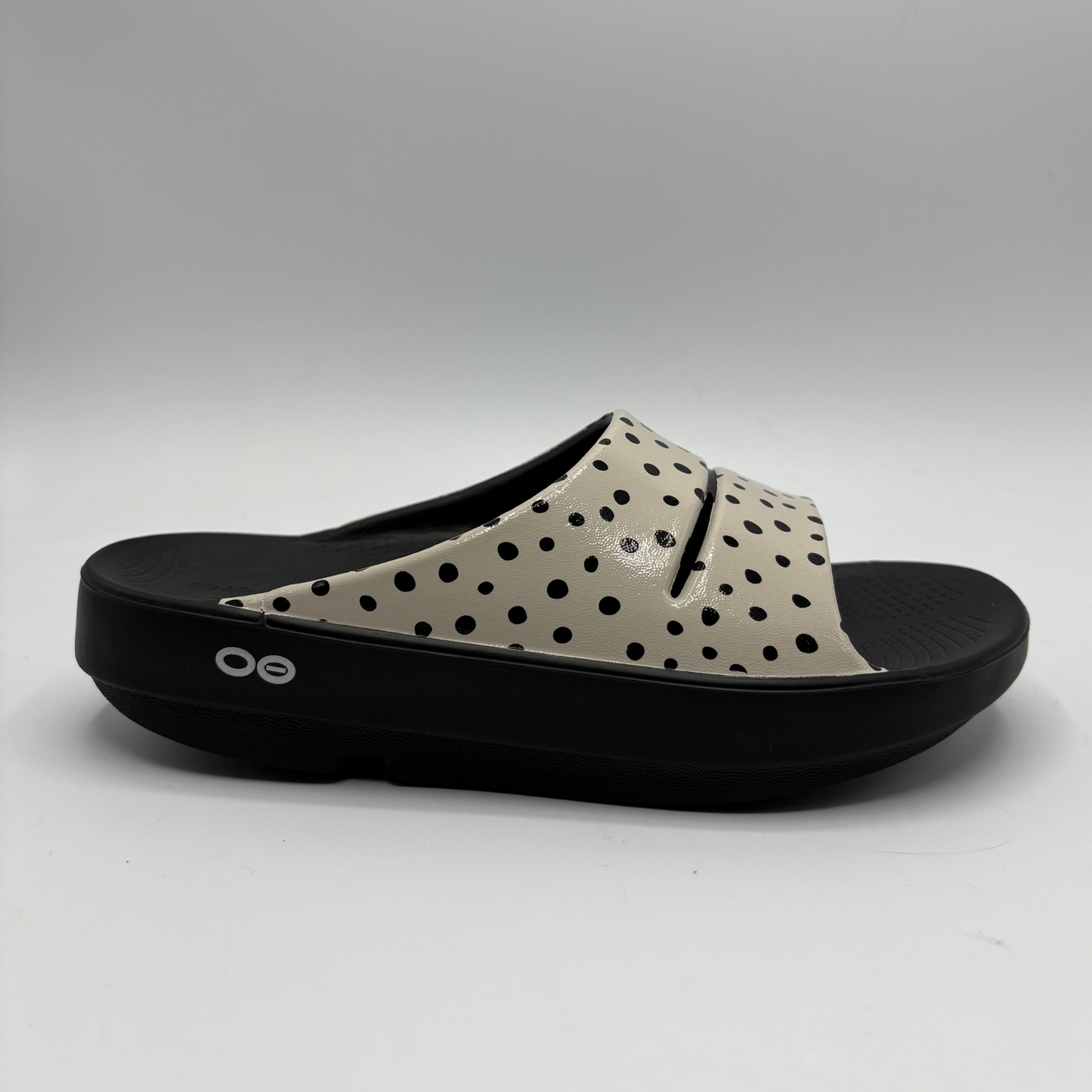 View of a cream coloured slide sandal with a black outsole
