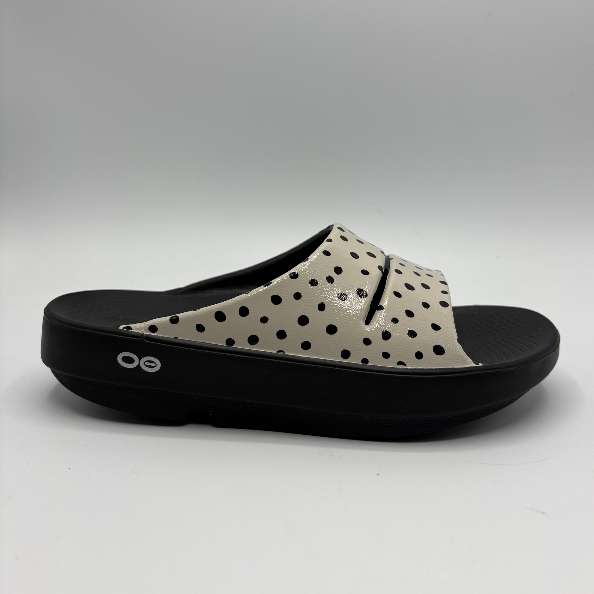 View of a cream coloured slide sandal with a black outsole
