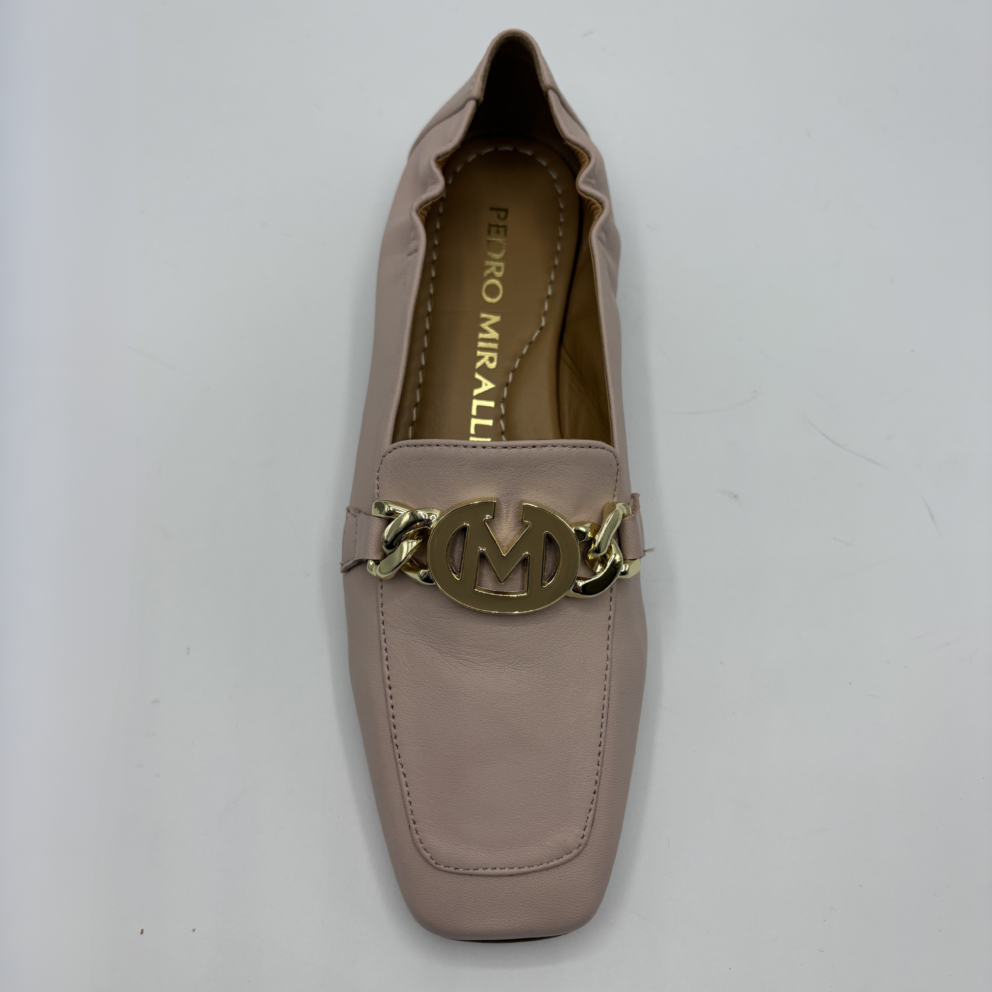 Top view of a leather loafer with a gold accent