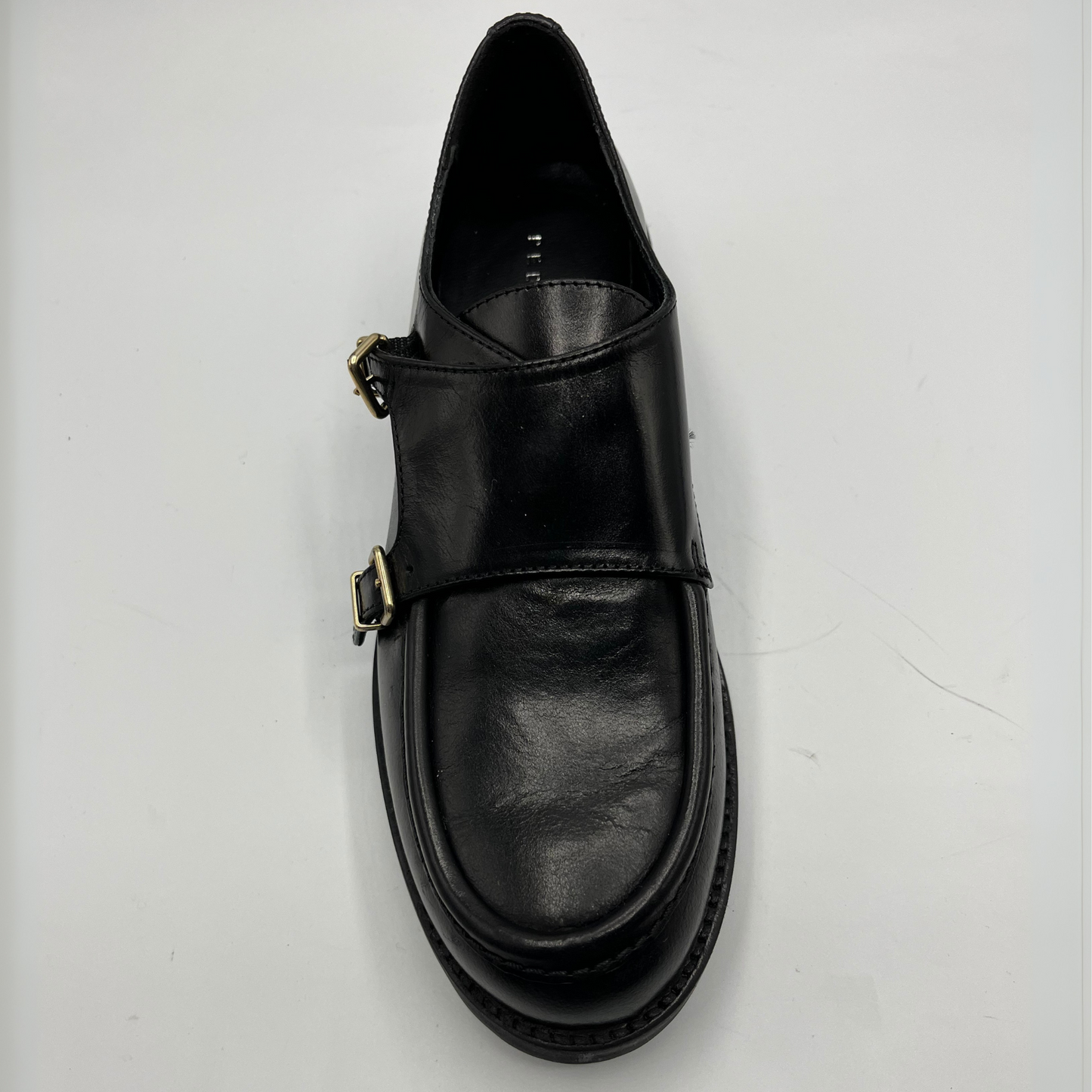 Black leather shoe with a buckle on a white background