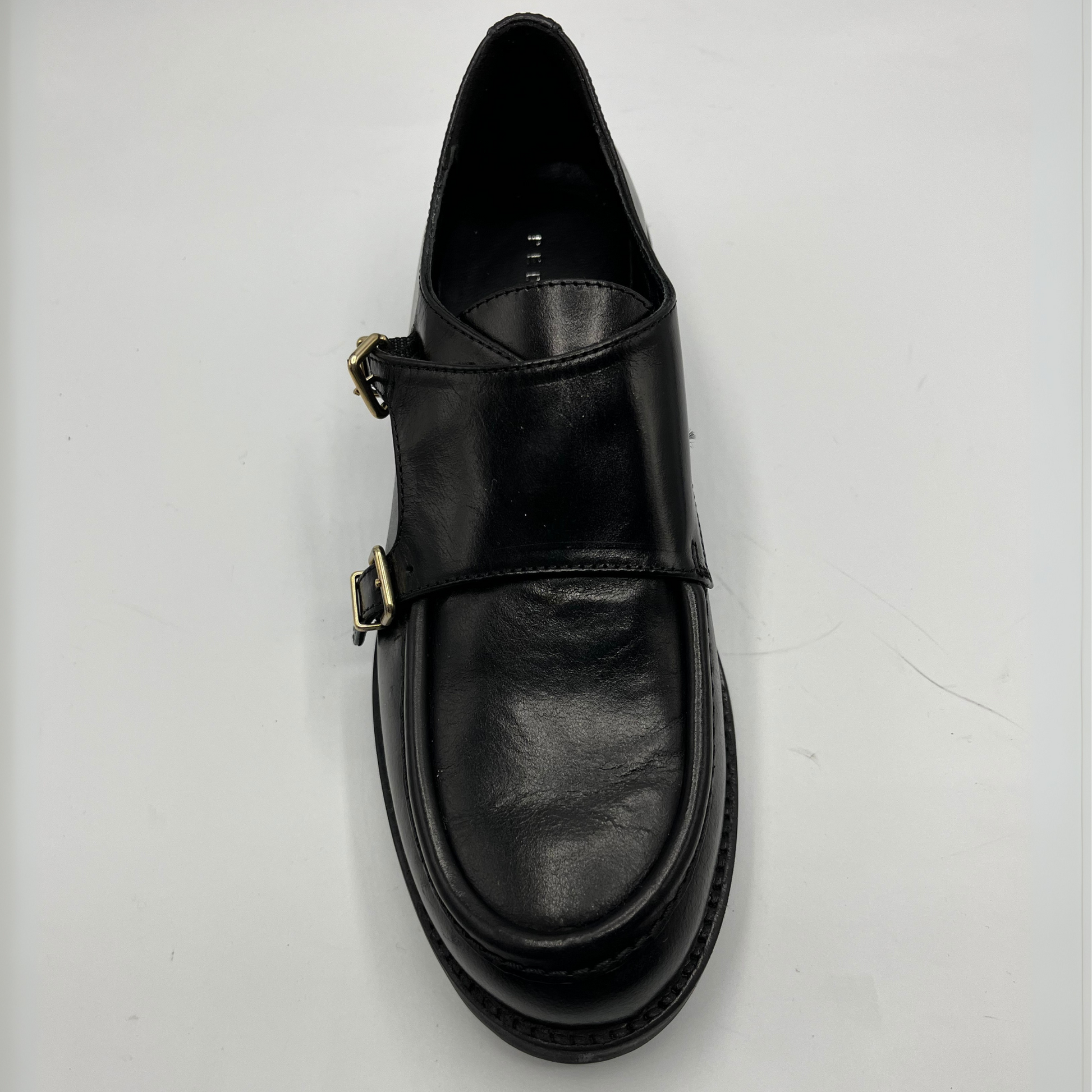 Black leather shoe with a buckle on a white background