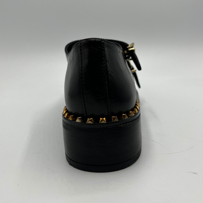 Black shoe with gold studs on a white background