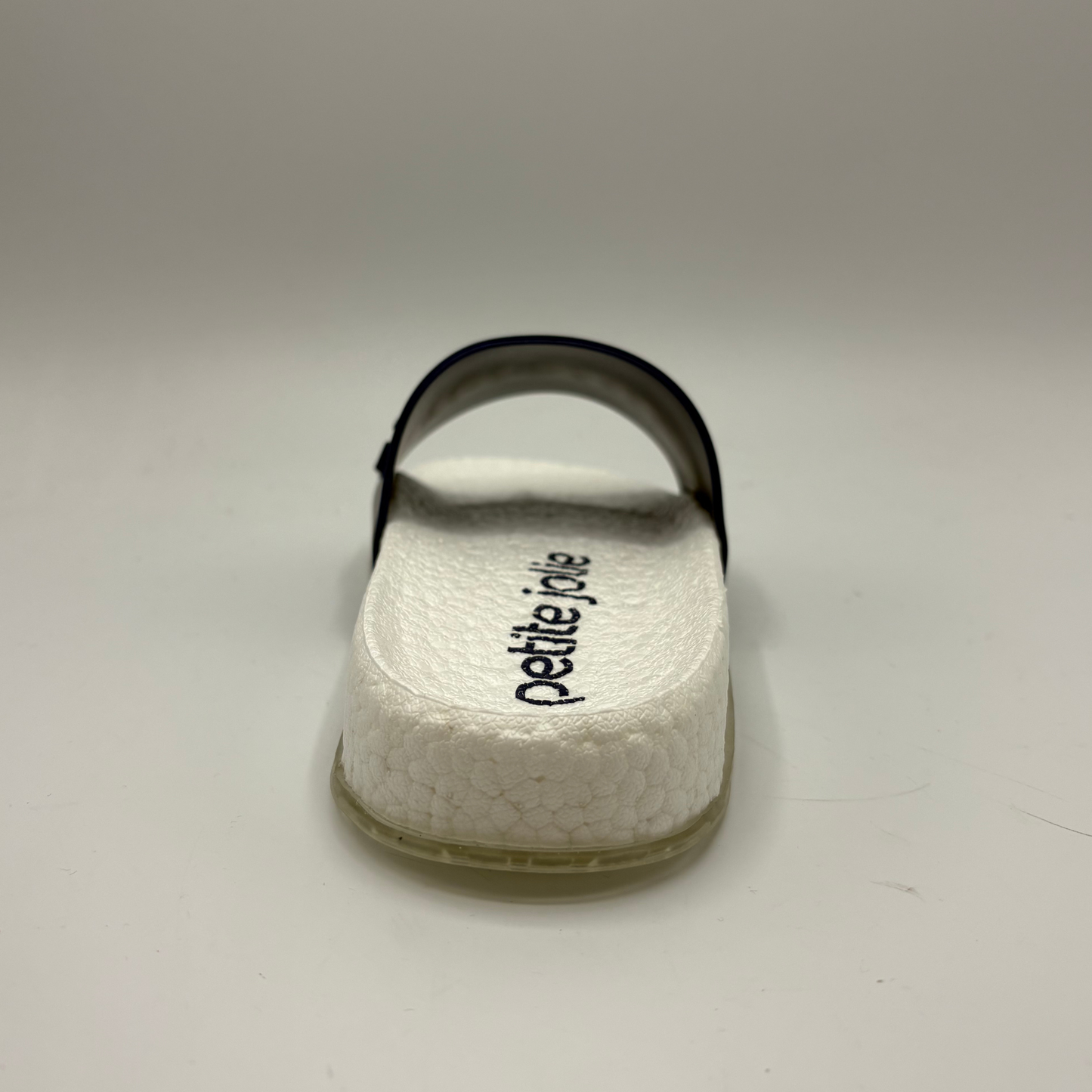 White sandal with 'petite jolie' branding on a light gray background