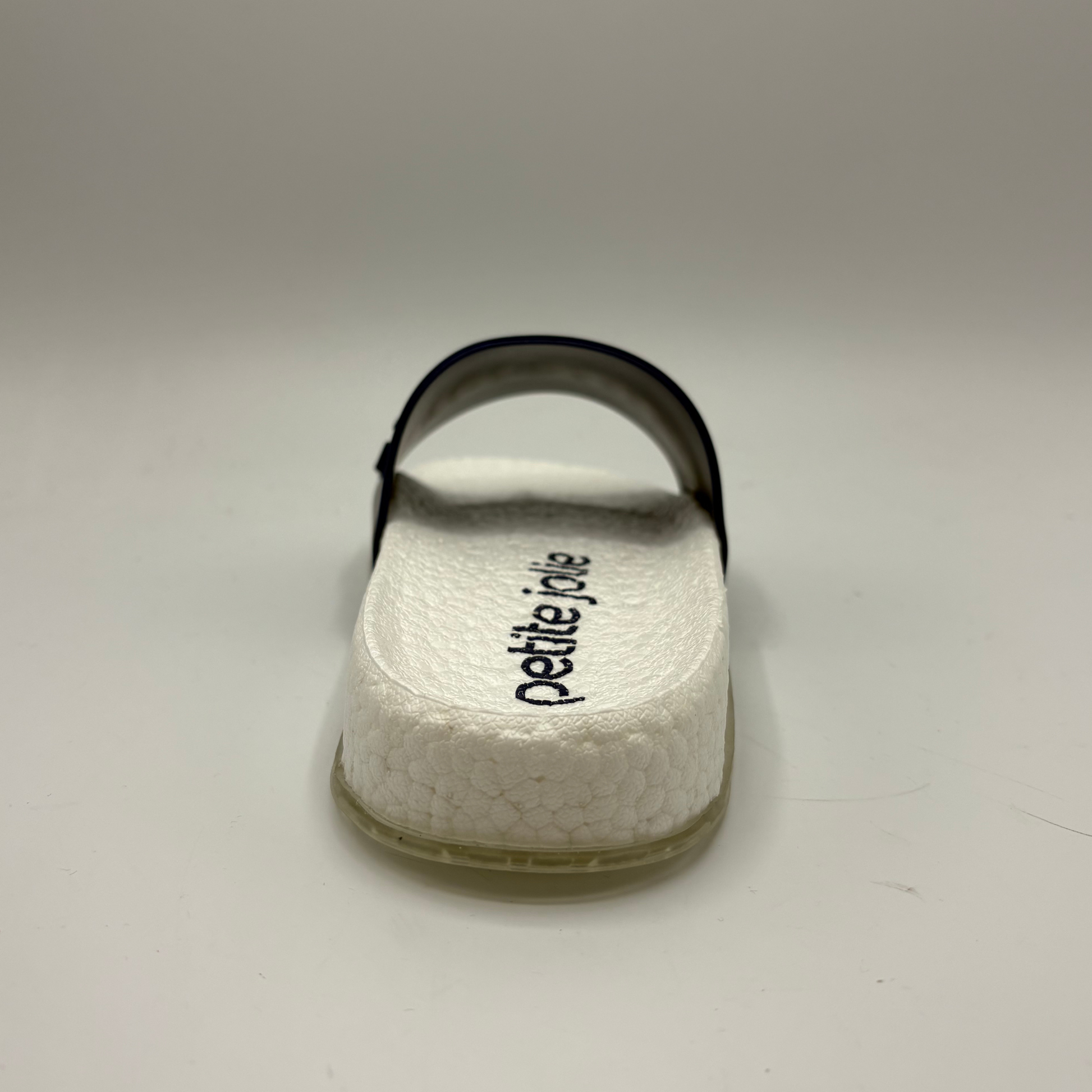 White sandal with 'petite jolie' branding on a light gray background
