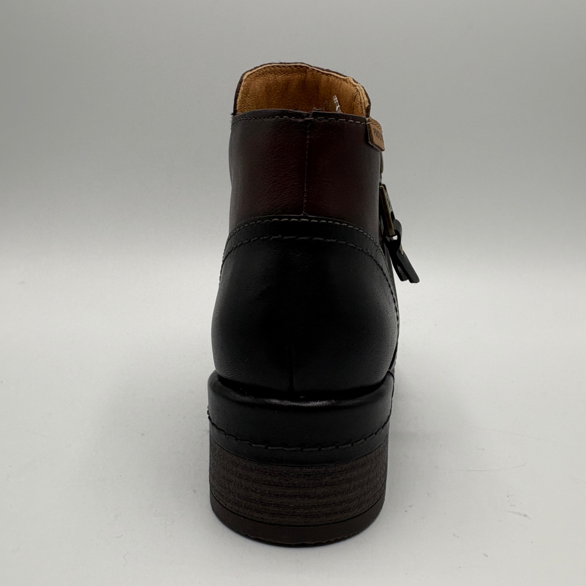 Back view of a brown leather ankle boot with a stacked heel and side zipper closure