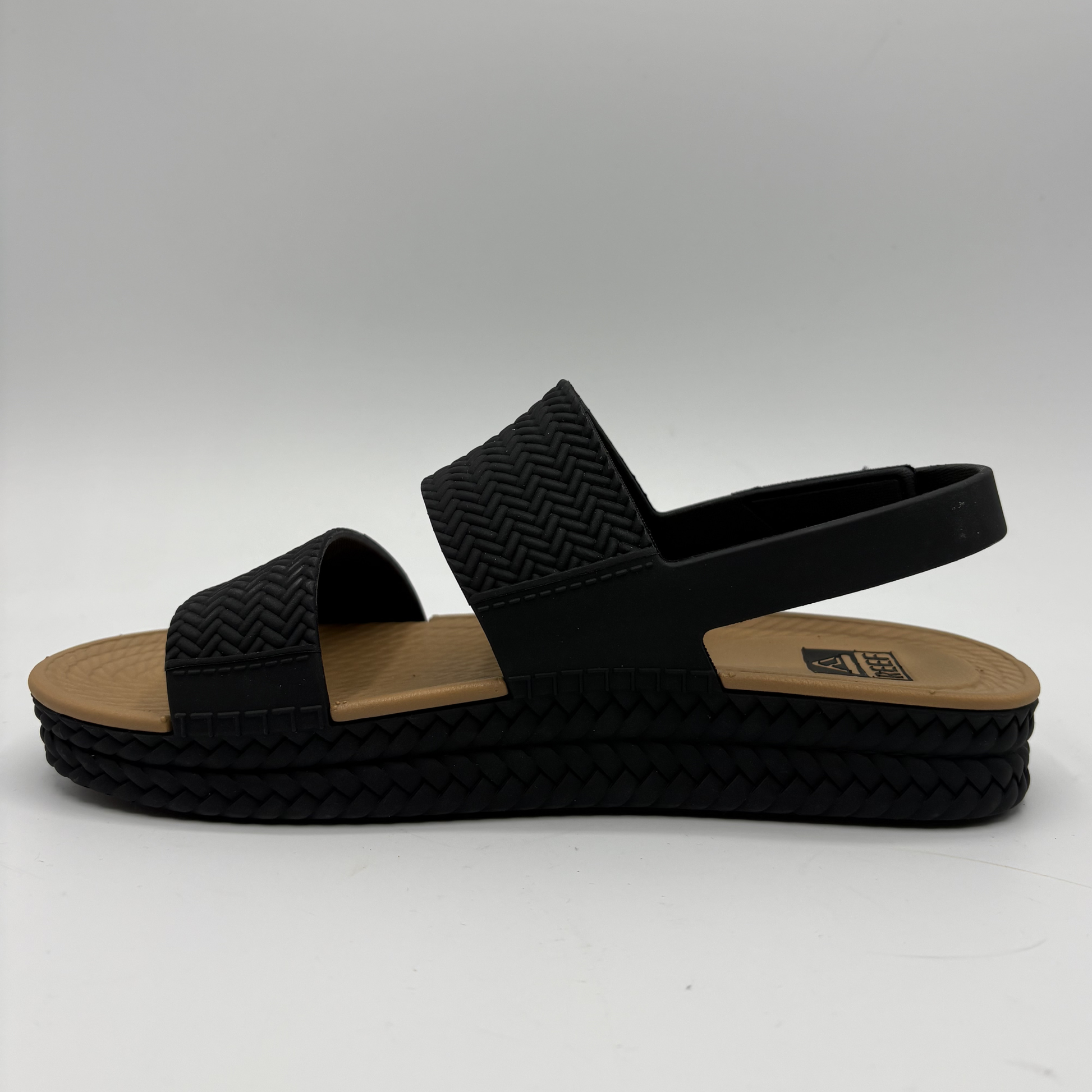 Left facing view of a black and tan braided strap sandals