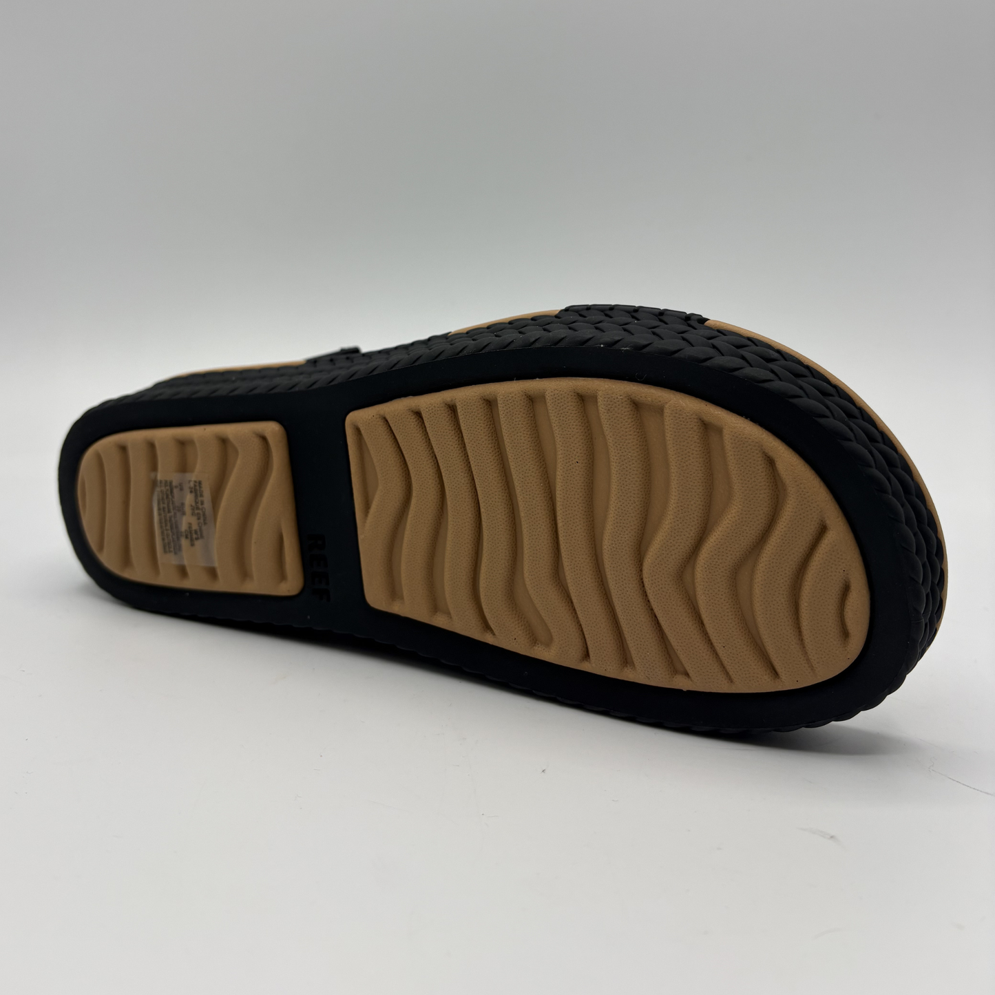 Bottom view of a black and tan braided strap sandals