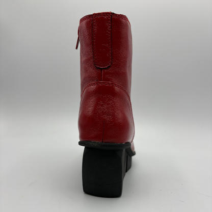 A red leather ankle boot shown from the back, featuring a black block heel and a side zipper, photographed against a neutral gray background.