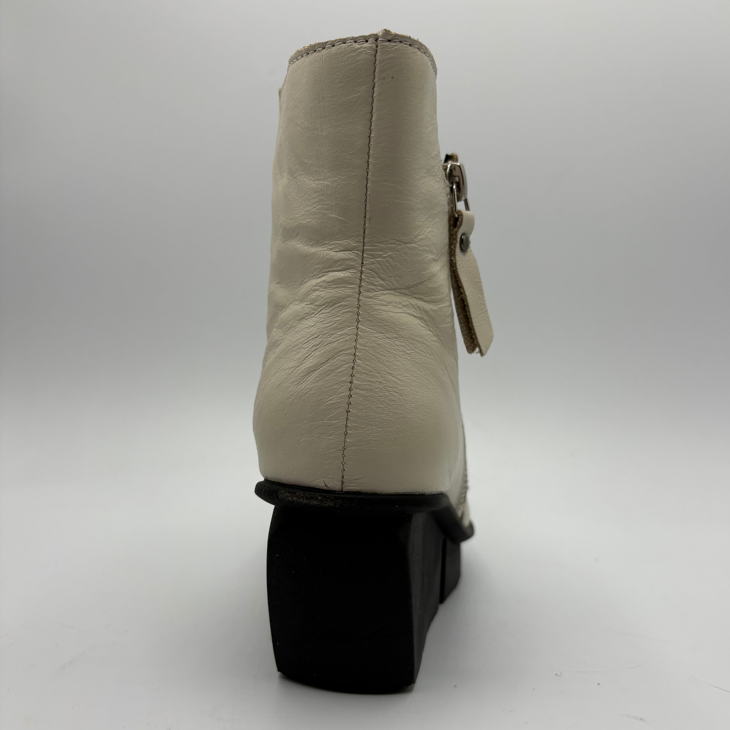 A beige leather ankle boot shown from the back, featuring a black block heel and a side zipper with a leather tag, set against a plain light gray background.
